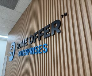 Dimensional acrylic wall sign with black and blue letters on wood paneling in Corona, CA.